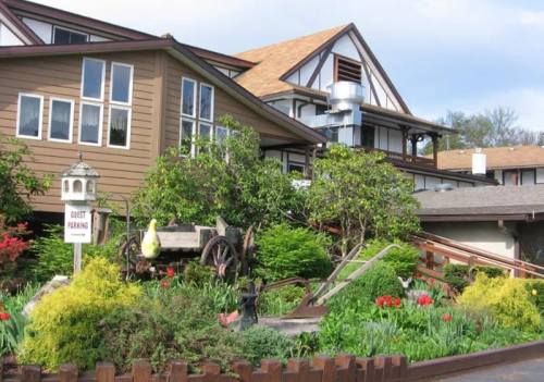 A charming building with a garden featuring colorful flowers and a vintage cart, labeled "Guest Parking."