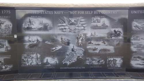 A memorial wall honoring the U.S. Navy, featuring images and events from various wars and conflicts.