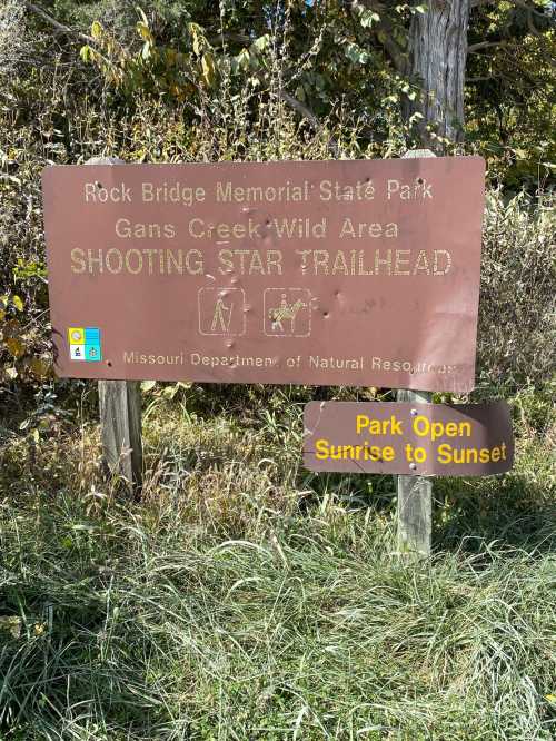 Sign for Rock Bridge Memorial State Park, indicating the Shooting Star Trailhead and park hours from sunrise to sunset.