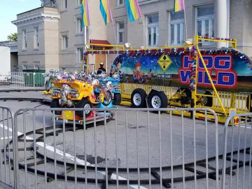 Colorful amusement ride called "Hog Wild" with small cars on a circular track, set up at a fair or festival.