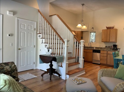 Cozy living space featuring a staircase, kitchen area, and comfortable seating with natural light.