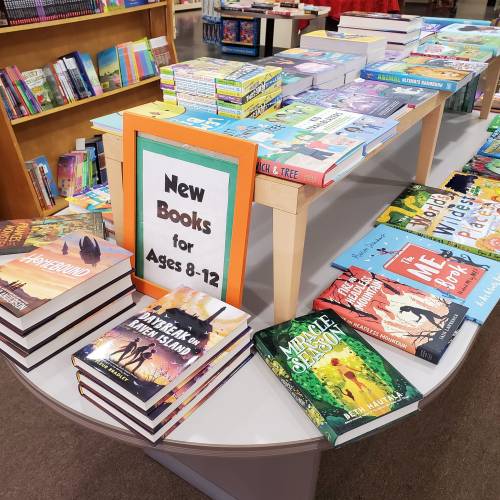 A display table featuring new books for ages 8-12, with colorful covers and various titles stacked and arranged.