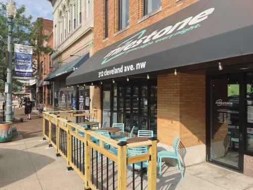 Exterior of Milestone restaurant with a patio, located at 312 Cleveland Ave NW, surrounded by brick buildings.
