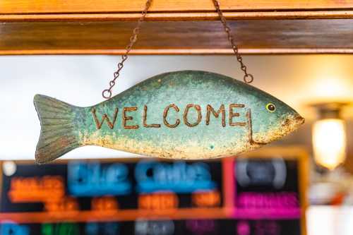 A decorative fish-shaped sign hanging with the word "WELCOME" painted on it.