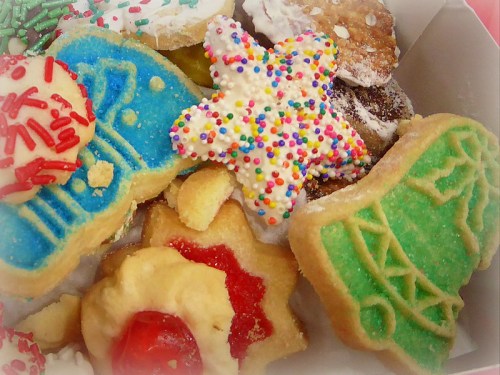 A colorful assortment of decorated cookies, including stars, Christmas trees, and various festive shapes.