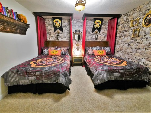 A themed bedroom with two beds, stone wall decor, and Hogwarts-inspired bedding and accessories.