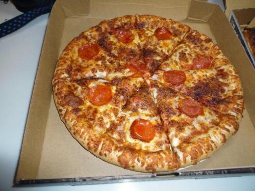 A pepperoni pizza with a golden crust, sliced into eight pieces, in a cardboard pizza box.
