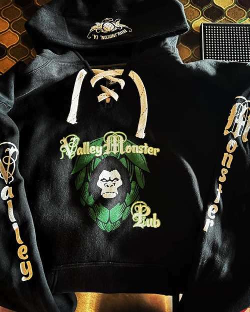 Black cropped hoodie featuring "Valley Monster Pub" logo with a gorilla design and lace-up front.