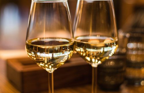 Two elegant wine glasses filled with white wine, reflecting warm light in a cozy setting.
