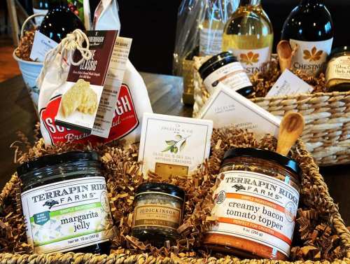 A display of gourmet food items, including jellies, spreads, and crackers, arranged in a woven basket.