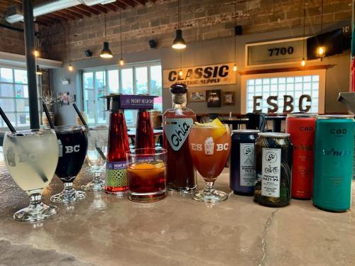 A variety of colorful drinks displayed on a bar counter, including cocktails and CBD beverages, in a stylish setting.