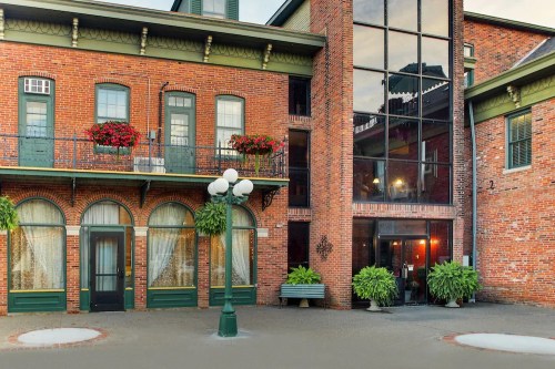 Historic brick building with large windows, balconies adorned with flowers, and a charming courtyard.