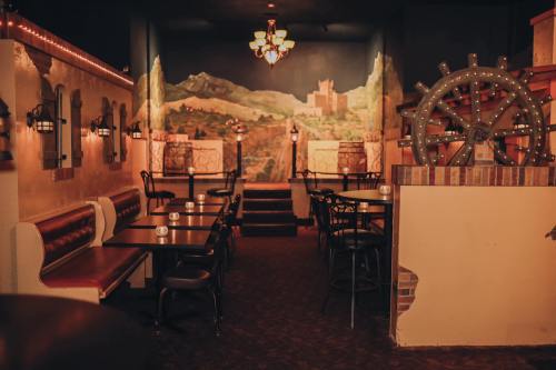 Cozy restaurant interior with tables, a mural of mountains, and a decorative ship's wheel. Warm lighting creates an inviting atmosphere.