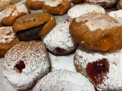 A tray of assorted pastries, including powdered sugar-coated donuts and filled treats with icing.
