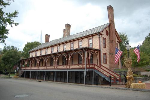 Historic building with a wooden facade, multiple chimneys, and American flags, set against a cloudy sky.