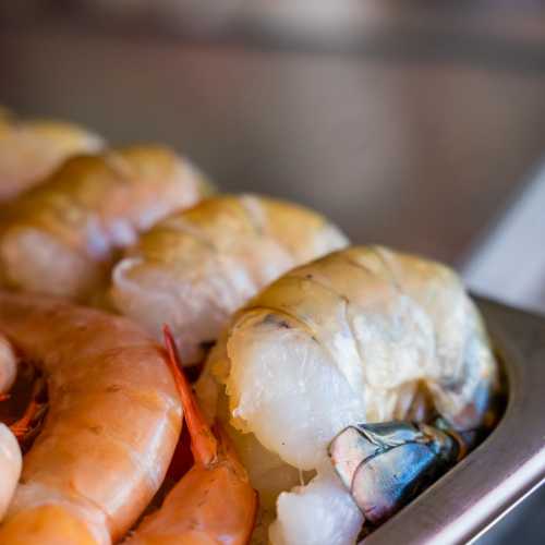 Close-up of various fresh shrimp, showcasing their vibrant colors and textures on a wooden surface.