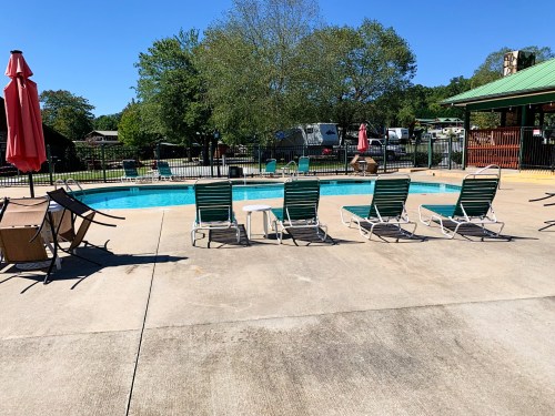 A sunny pool area with lounge chairs, umbrellas, and a clear blue sky in the background.