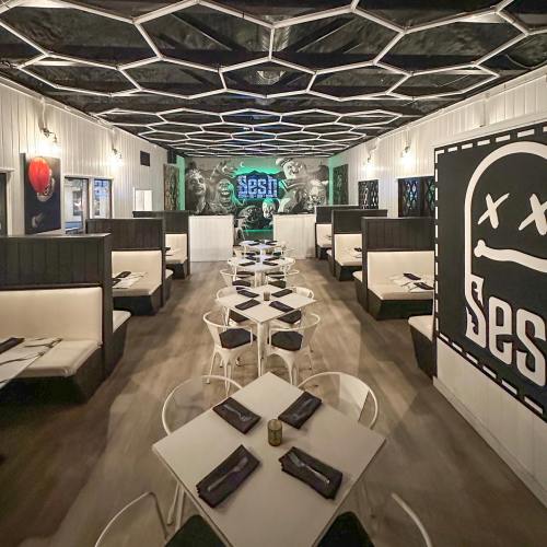 Modern restaurant interior with hexagonal ceiling, black and white decor, and tables set for dining.