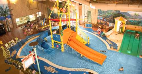 Indoor water park featuring slides, a play structure, and a lazy river, with families enjoying the water.