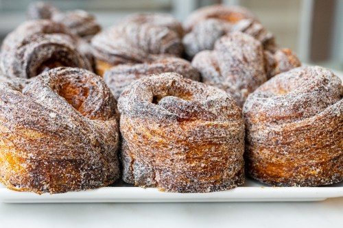 A close-up of freshly baked, sugar-coated pastries arranged on a white platter.
