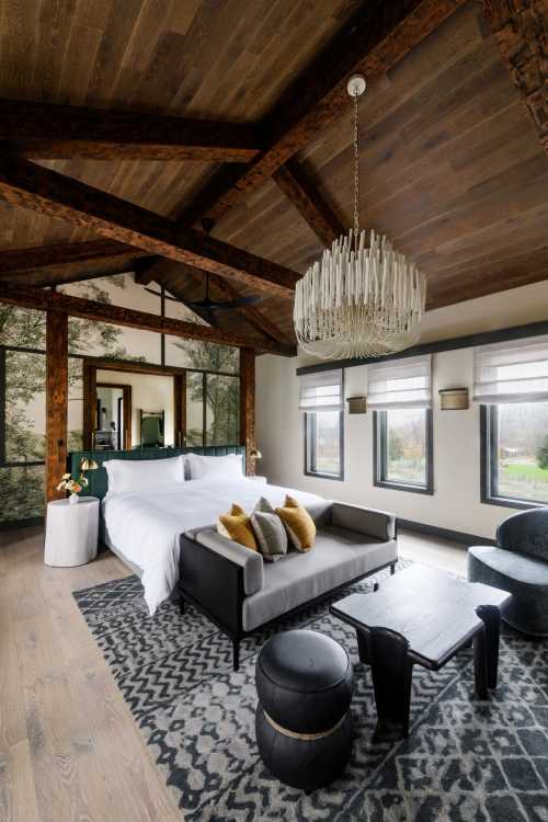 A modern bedroom with a wooden ceiling, large windows, a plush bed, and stylish furniture, featuring a cozy atmosphere.