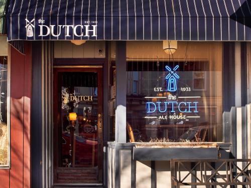 Exterior of The Dutch Ale House, featuring a blue neon sign and a striped awning, established in 1933.