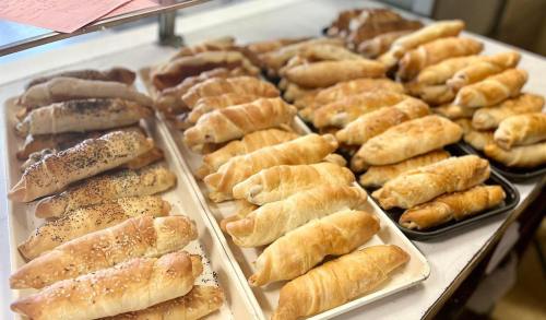 A variety of freshly baked pastries arranged on trays, showcasing different shapes and toppings.