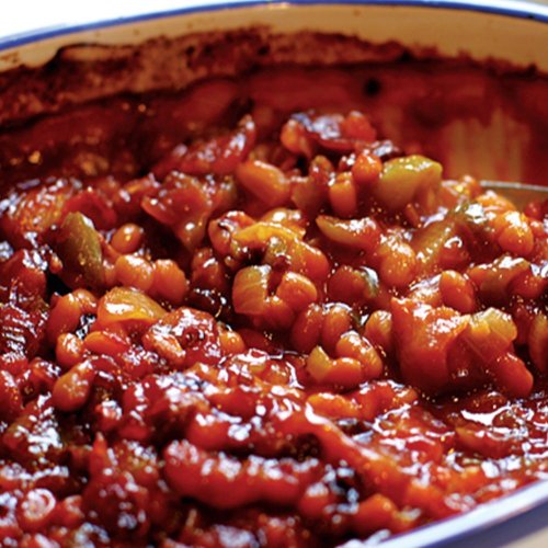 A close-up of a hearty bean chili in a baking dish, featuring beans, vegetables, and a rich tomato sauce.