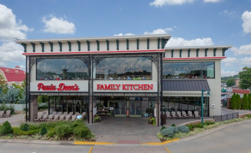 Exterior view of Paula Deen's Family Kitchen, featuring a large sign and a welcoming entrance surrounded by greenery.