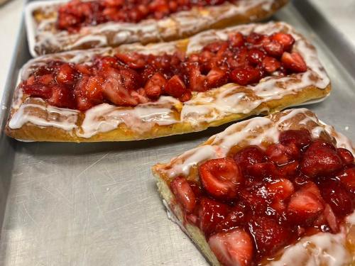 Three rectangular pastries topped with strawberries and icing, arranged on a silver tray.