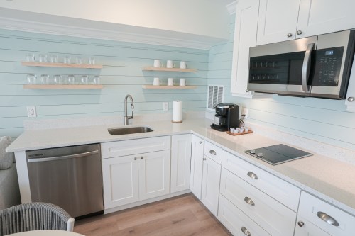 Modern kitchen with light blue walls, white cabinets, stainless steel appliances, and a clean countertop setup.
