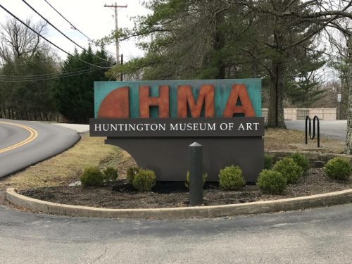 Sign for the Huntington Museum of Art, featuring the acronym "HMA" and surrounded by greenery.
