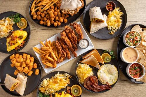 A variety of delicious dishes including fried chicken, tacos, fries, and tater tots arranged on black plates.