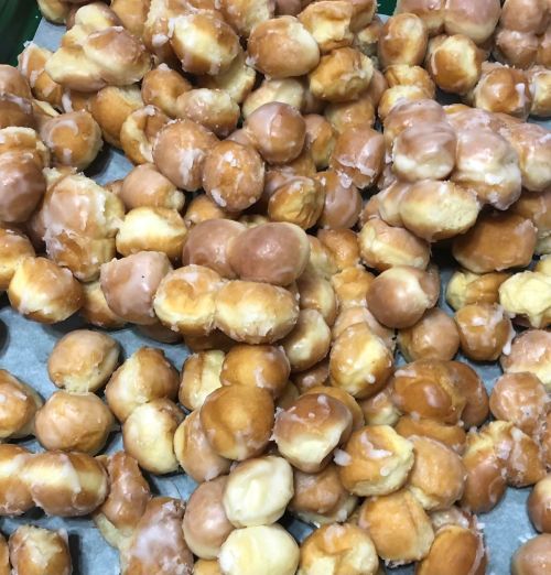 A close-up of a pile of glazed doughnut holes in various shades of brown and cream.