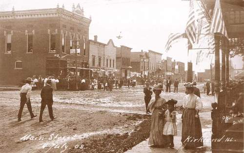 Historic sepia photo of Main Street in Kirkland, IL, from July 1908, featuring people and storefronts.