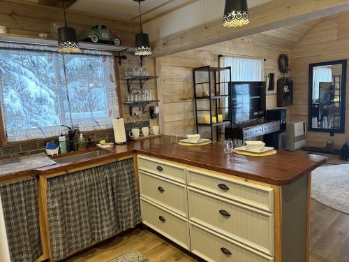 Cozy kitchen with wooden accents, a large island, modern appliances, and a view of snowy outdoors through a window.