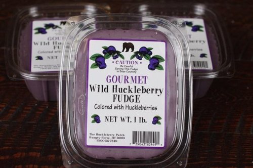 A container of gourmet wild huckleberry fudge, labeled with a bear caution sign and colorful huckleberry graphics.