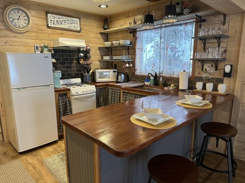 Cozy farmhouse kitchen with wooden accents, a bar counter, and modern appliances, featuring a warm, inviting atmosphere.