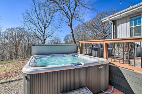A hot tub on a deck surrounded by trees, with a clear blue sky in the background.