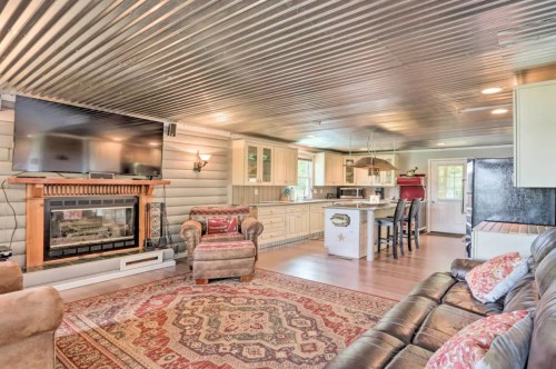 Cozy living room with a fireplace, leather sofa, patterned rug, and open kitchen area with modern appliances.