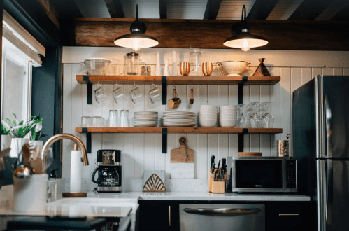 A modern kitchen with open shelves displaying glassware and dishes, a coffee maker, and a microwave on a countertop.