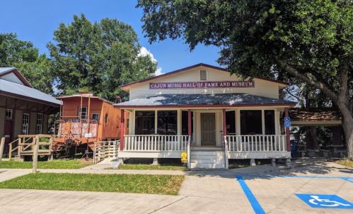 Cajun Music Hall of Fame and Museum, a charming building with a porch, surrounded by trees and a blue sky.