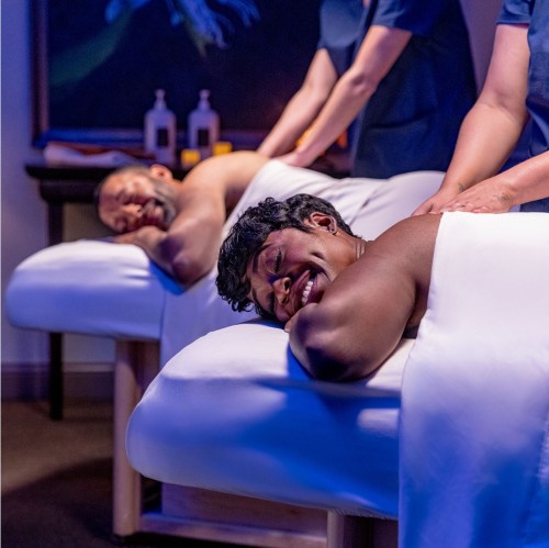 Two people enjoying a relaxing massage in a serene spa setting, with therapists providing treatment.