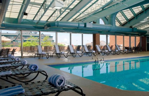 Indoor swimming pool with lounge chairs, large windows, and a bright, airy atmosphere.