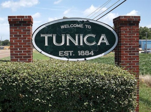 Welcome sign for Tunica, established in 1884, surrounded by greenery and brick pillars.