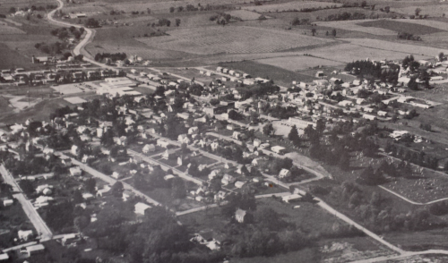 Aerial view of a small town with houses, roads, and fields, showcasing a rural landscape.