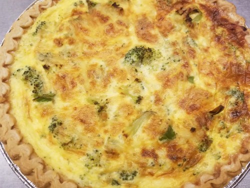 A golden-brown quiche filled with broccoli and cheese in a flaky crust.