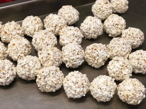 A tray of round popcorn balls, clustered together, with a light, fluffy appearance.