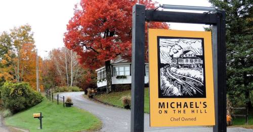 Sign for "Michael's on the Hill" with a scenic autumn landscape and colorful trees in the background.
