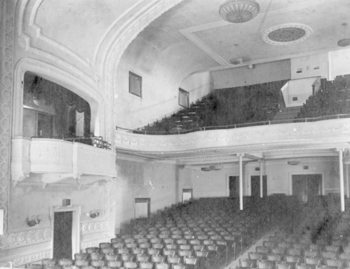 Interior of a vintage theater, featuring ornate architecture and rows of empty seats.